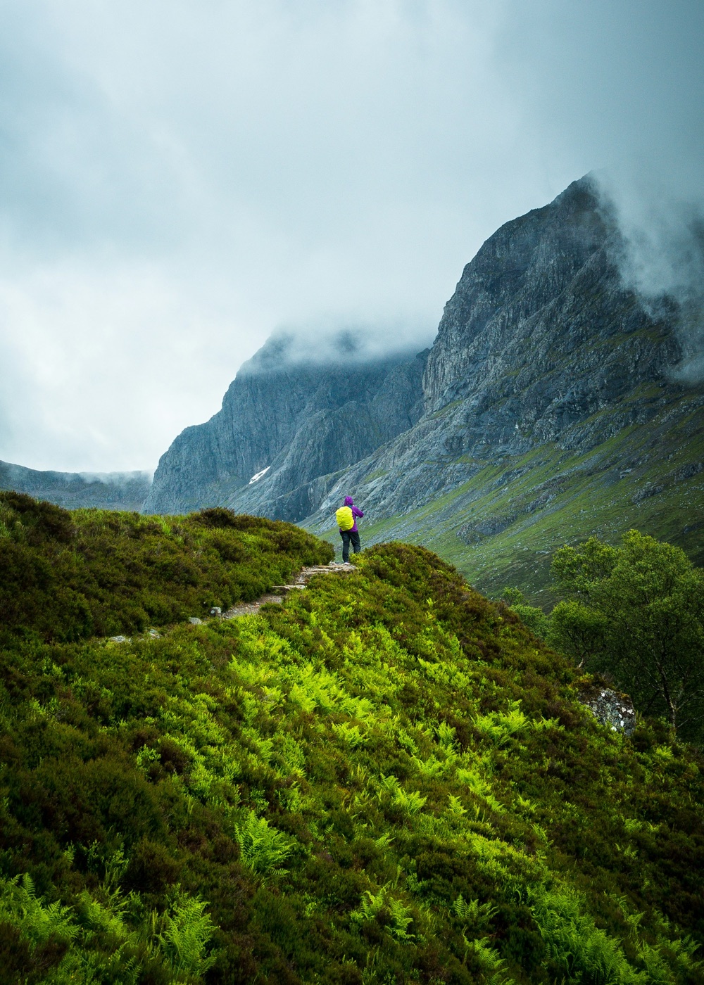A solo hiker on a misty Highland ridge, mountains in the background